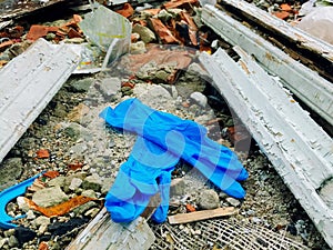 Disposable medical gloves on ground with other plastic trash on landfill. How to dispose used medical gloves right after