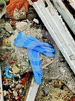 Disposable medical gloves on ground with other plastic trash on landfill. How to dispose used medical gloves right after
