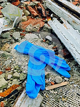 Disposable medical gloves on ground with other plastic trash on landfill. How to dispose used medical gloves right after