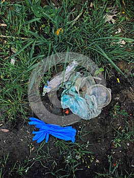 Disposable medical gloves on ground with single use plastic trash. How to dispose used medical gloves right after coronavirus pand