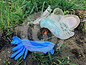 Disposable medical gloves on ground with single use plastic trash. How to dispose used medical gloves right after coronavirus