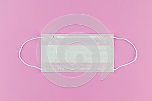 Disposable medical mask on a pink background close-up , concept shortage of medical masks during the coronavirus COVIND-19 pandemi