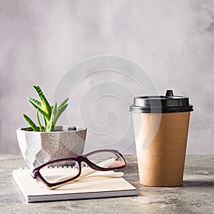 Disposable paper cup with coffee drink or tea notepad glasses on the desktop. Concept business lunch break zero waste.