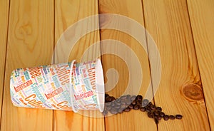Disposable paper cups and coffee beans on background light wood. photo