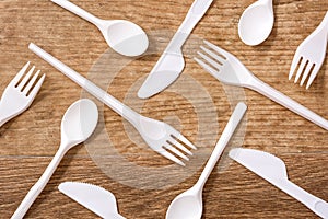 Disposable plastic cutlery on wooden table.