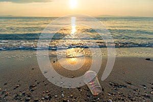Disposable plastic glass discarded on sandy sea coast ecosystem