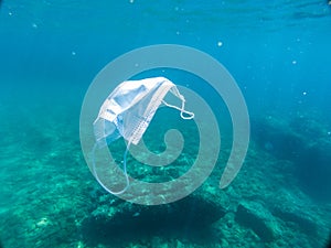 Disposable protection mask under the sea, residues of the covid-19 pandemic photo