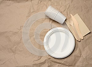 Disposable round white paper plates and cups on brown paper background