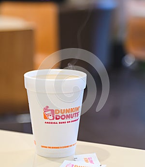 Dunkin donuts cup of hot coffee and sugar sachet on table