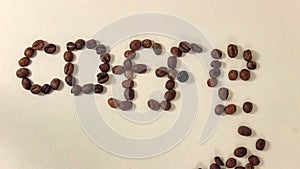 A disposable syringe that moves on a blue surface.Coffee beans that move on a light background and create the word COFFEE.