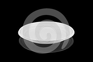 Disposable white plastic plate isolated on black background