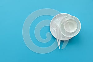 Disposable white plastic plates and  forks on blue background. Copy space. Top view. Eco and save earth concept