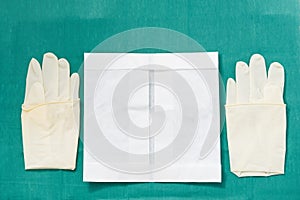 Disposible sterile rubber,one time used Gloves with paper package on green signature of surgery dress