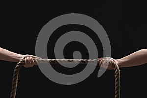 Dispute concept. Men pulling rope on black background, closeup. Space for text