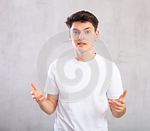 Disputing young man standing against background of grey unicolored wall