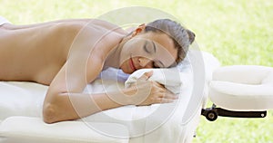 Disrobed woman lays belly down on table photo