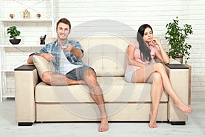 Dissapointed beautiful brunette woman in quarrel with her boyfriend. Indifferent man watching TV. photo