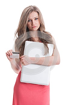 Dissapointed girl holding laptop and credit card photo