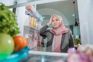 dissapointed woman while opening the fridge door photo