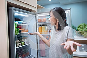 dissapointed woman while opening the fridge door photo