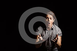 Dissapointed young handsome man gesturing, shouting over black background. photo