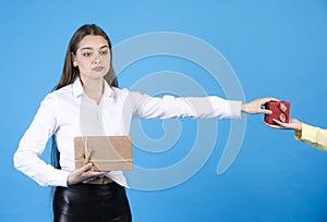 Dissatisfied brunette birthday girl waiting for gift, while holding out arm to small present box.