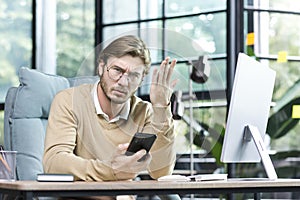 Dissatisfied businessman freelancer in glasses upset looking at camera man working