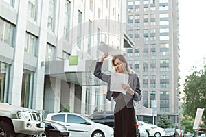 Dissatisfied businesswoman throwing stack of papers in the air in front of the office in the financial city district. Frustrated