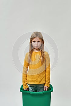 Dissatisfied caucasian little girl standing in bin