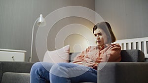 Dissatisfied and disappointed woman sitting on the sofa, watching TV and throwing popcorn