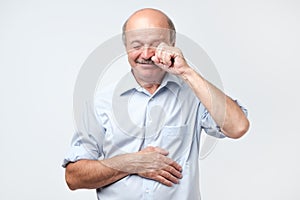 Dissatisfied disconcerted senior man crying and wiping tears