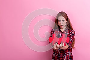 A dissatisfied girl, holds a large puzzle. On a pink background.