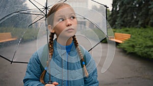 Dissatisfied little girl city street outside bad weather rain schoolgirl with umbrella learner school unhappy child kid