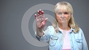 Dissatisfied senior woman showing stop gesture, age-related illnesses prevention