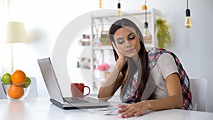 Dissatisfied woman looking at bills, shocked about expenses, planning budget