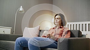 Dissatisfied woman sitting on the sofa, watching TV and throwing popcorn