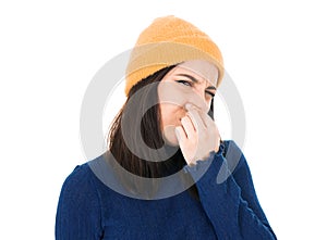Dissatisfied young woman holding finger on nose has disgusting expression on face, something stinky, isolated on white background