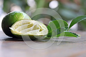 Dissect lime is squeeze out with full lime and the leafs on the wooden table.