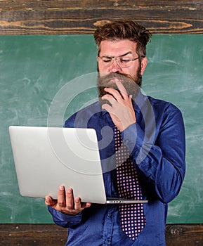 Distance education concept. Surfing internet. Hipster teacher wear eyeglasses and necktie holds laptop surfing internet