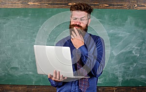 Distance education concept. Teacher bearded man with modern laptop surfing internet chalkboard background. Surfing