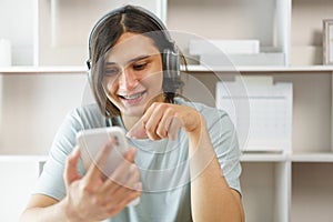 Distance education concept, Teen boy in headphone to listen music and use phone after study online