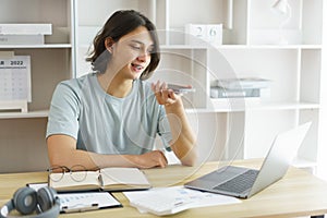 Distance education concept, Teen boy talking on phone and using laptop to lesson class online