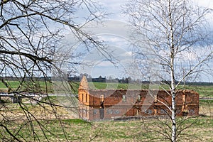 in the distance on the field stands an old, ruined, abandoned building made of red brick.