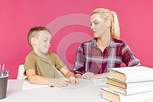 Distance homework with mother at home at quarantine time. Boy with mom sitting at the desk and studying.