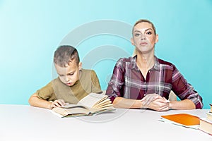 Distance homework with mother at home at quarantine time. Boy with mom sitting at the desk and studying.