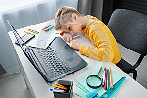 Distance learning, the boy fell asleep at the table doing homework. The concept of online education, home education, technology,