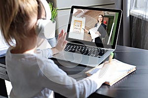 Distance learning. Cheerful little girl girl in headphones using laptop studying through online e-learning system.