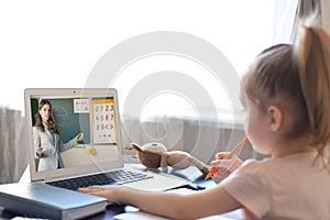 Distance learning. Cheerful little girl using laptop computer studying through online e-learning system