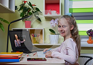 Distance learning concept. Happy girl runs the school program remotely using laptop