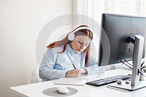 Distance learning, education and work. Professional businesswoman working using on computer while holding pen on notepad